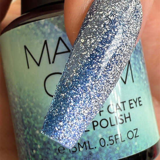 Close-up of a glittery blue nail polish with a visible brand label.