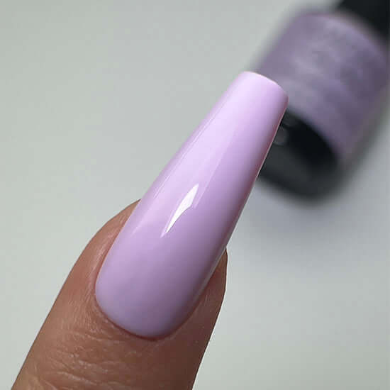 Close-up of a hand with a long, lavender-pink nail against a neutral background