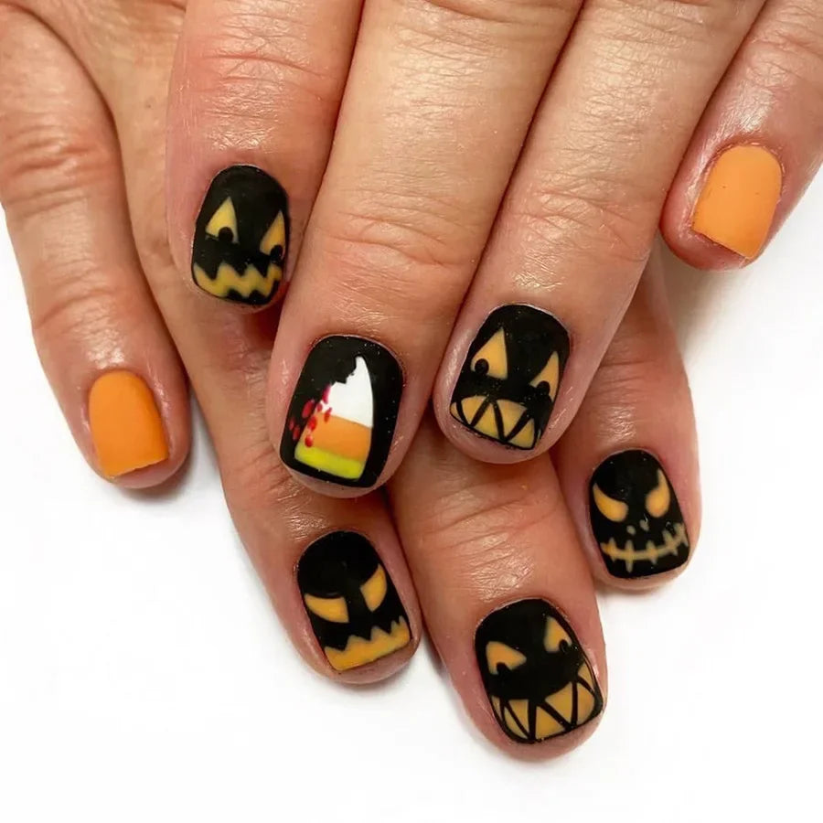Halloween-themed nail art with jack-o'-lantern faces on a white background