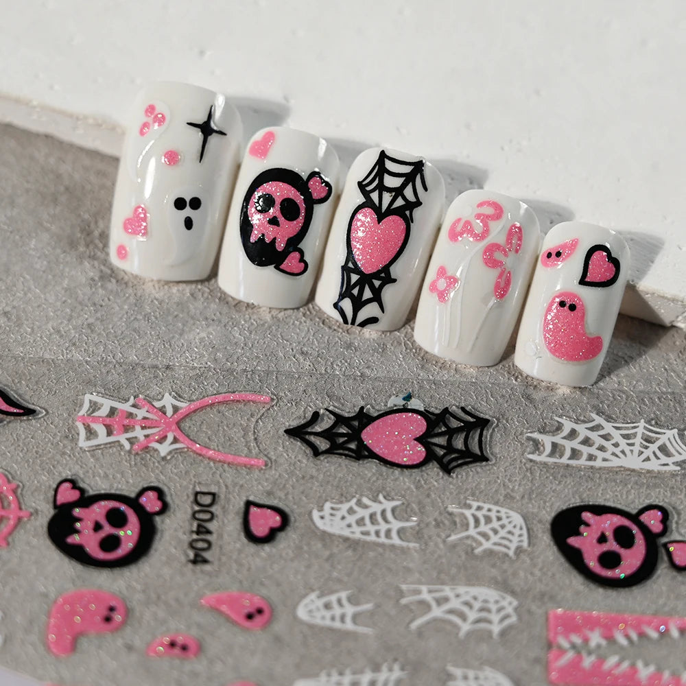 Set of nail art stickers with skull, heart, and spider web designs on a gray surface.