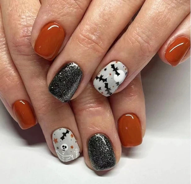 Nails with Halloween-themed designs and orange polish on a white background