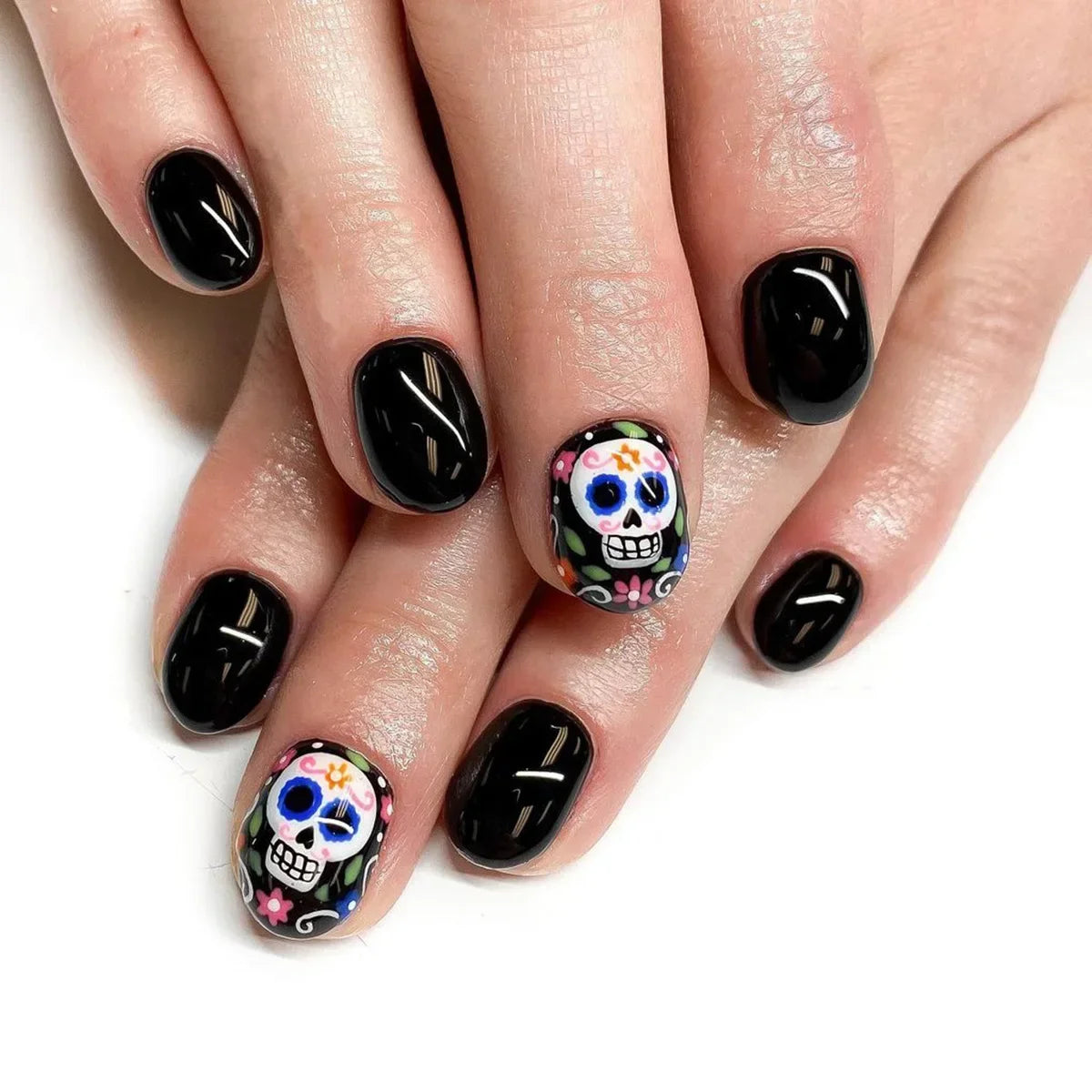 Nails with black polish and colorful skull designs on a white background