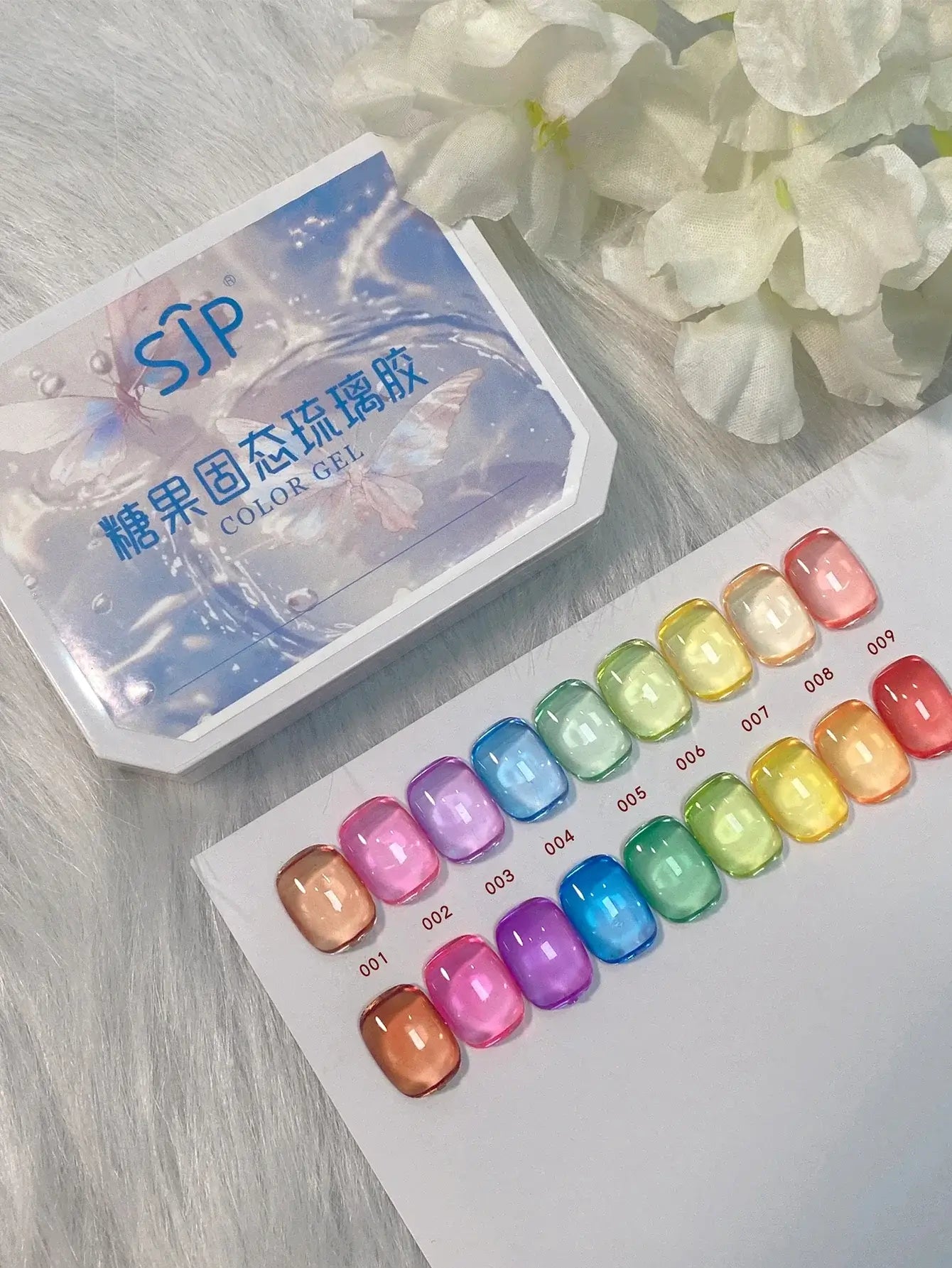 Color gel swatches with a 'SIP' container on a light wooden surface with white flowers.