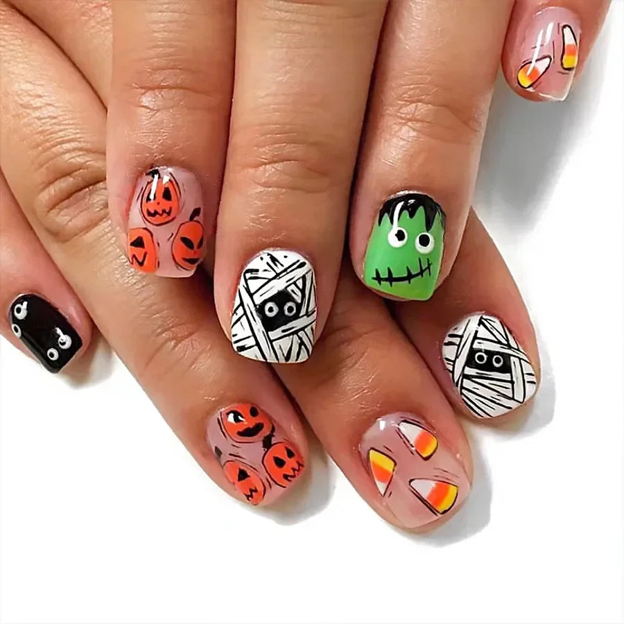 Halloween-themed nail art on a hand with pumpkins, mummies, and Frankenstein designs.