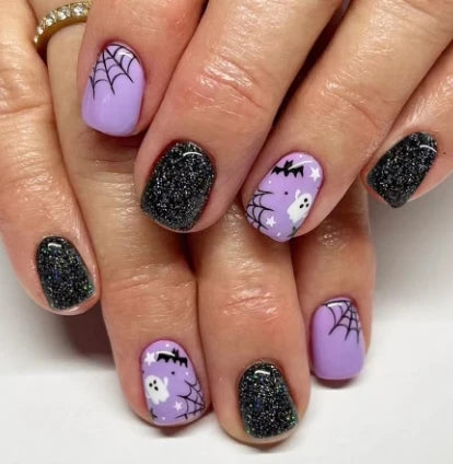 Nails with Halloween-themed design featuring purple, black, and glittery accents.