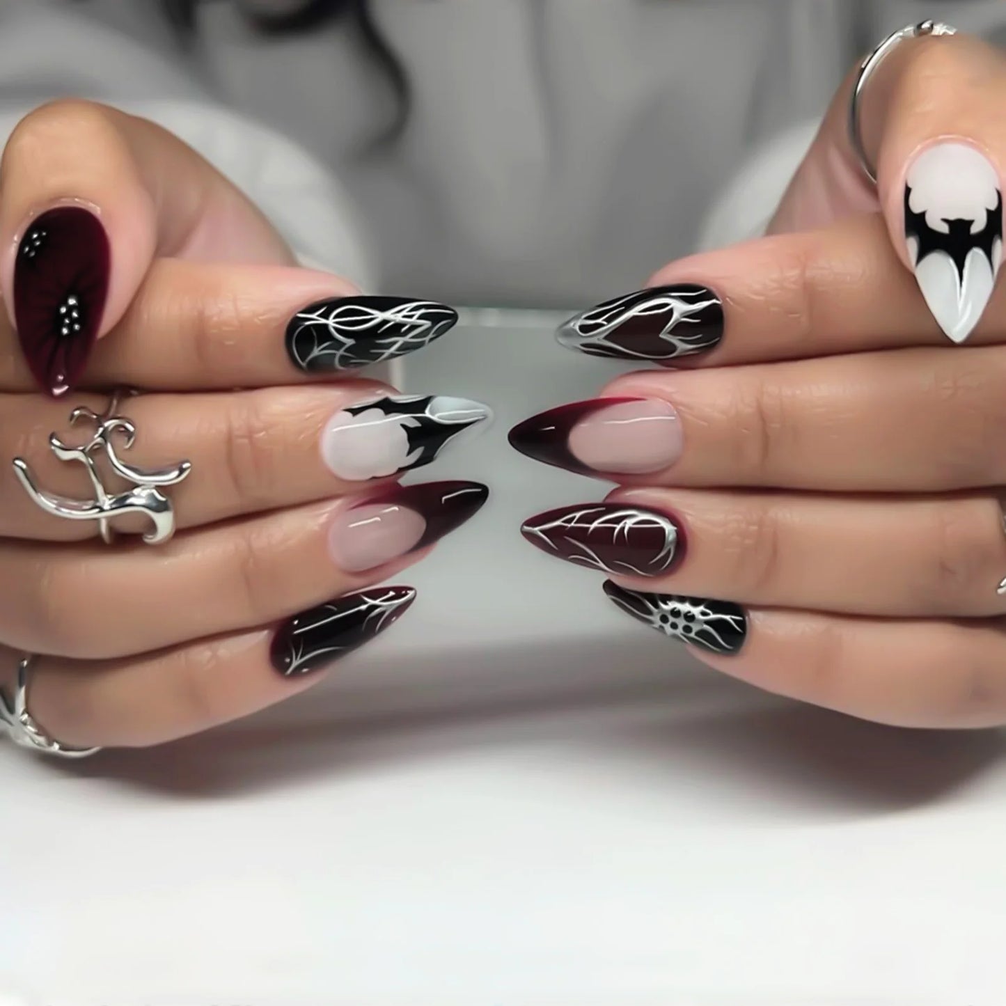 Close-up of hands with black and white halloween spider nail art on a neutral background