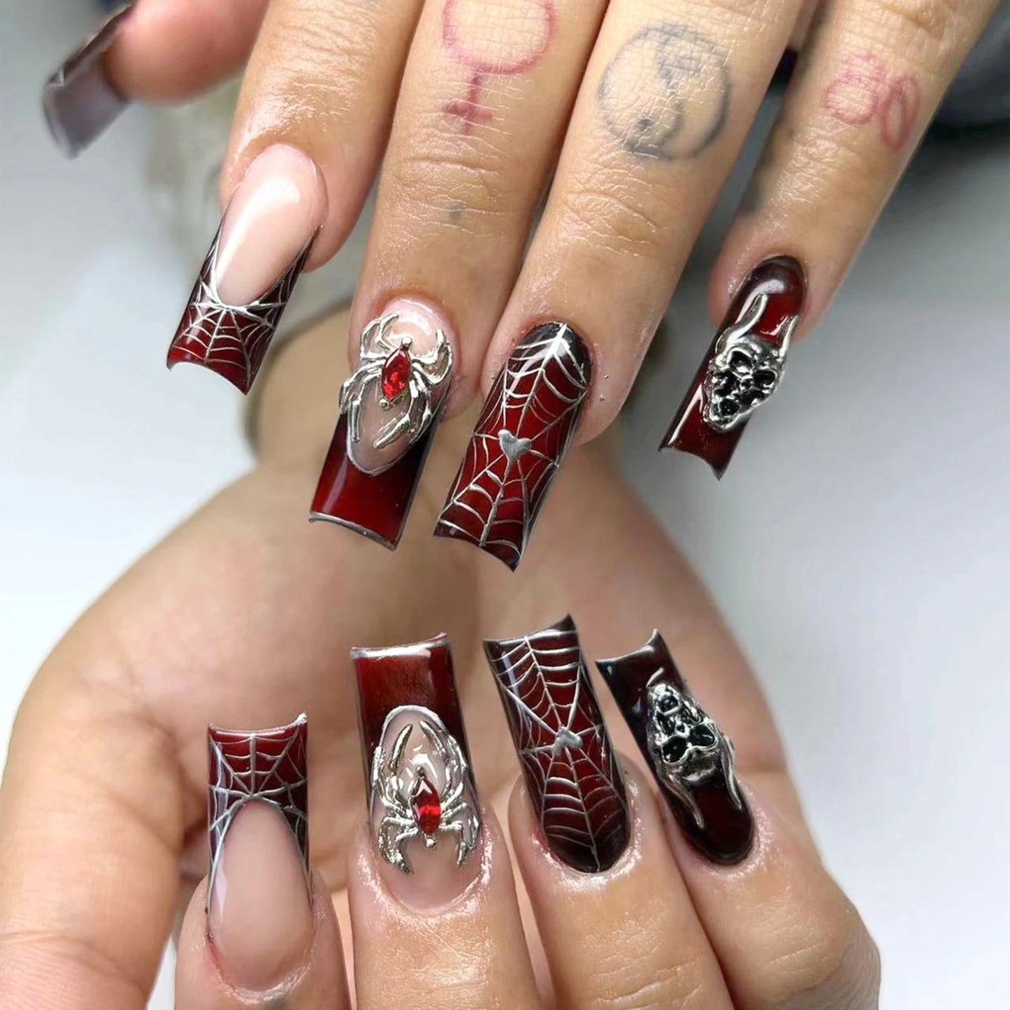 Nails with Halloween-themed design featuring spiders, webs, and red accents on a white background.