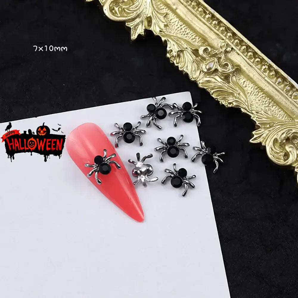 Halloween Punk Nail Charms Black spider decorations on a pink nail with a gold frame and Halloween-themed label in the background.