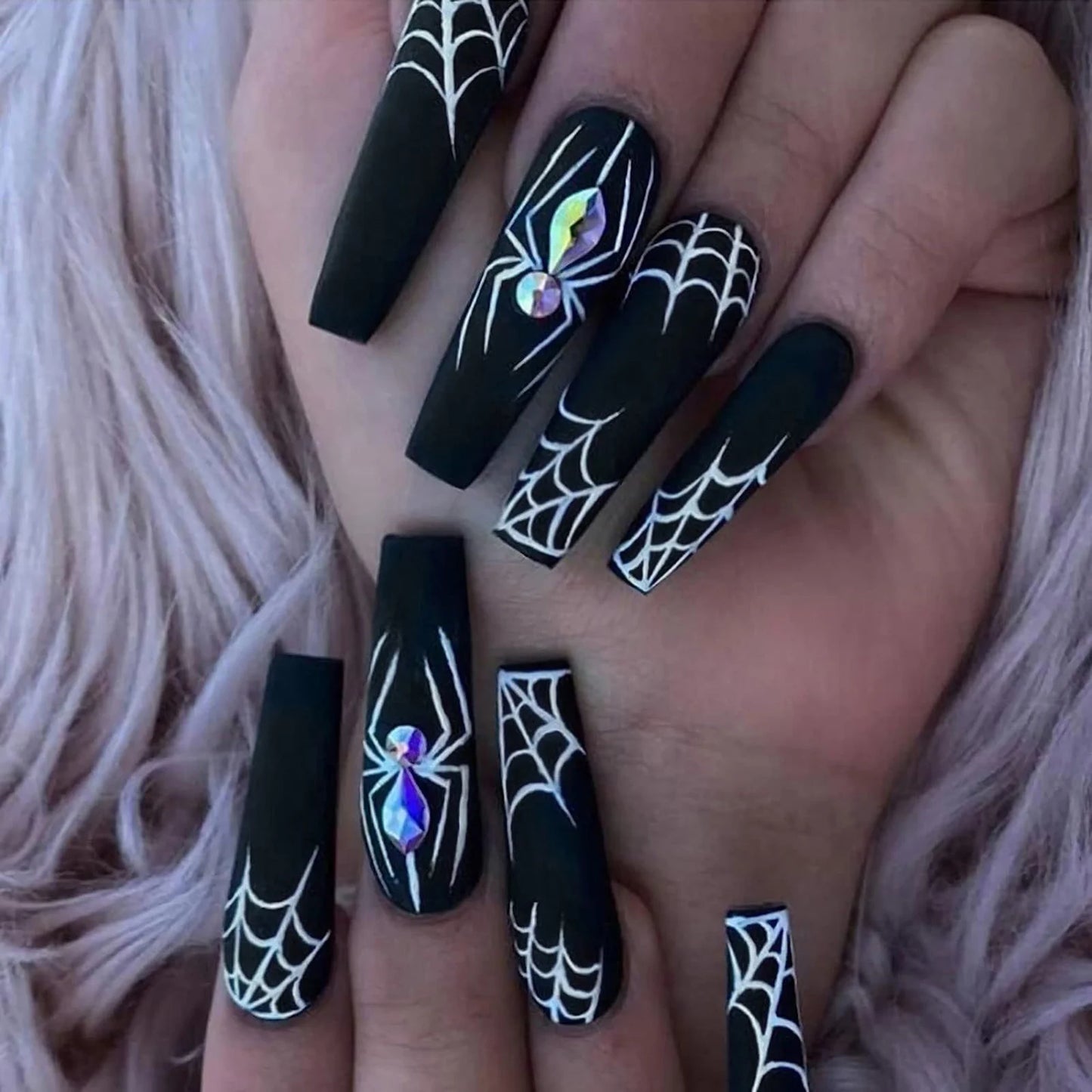 Black nail art with spider webs and rhinestones on a hand