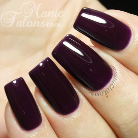 Close-up of a hand with dark purple nail polish on a light background