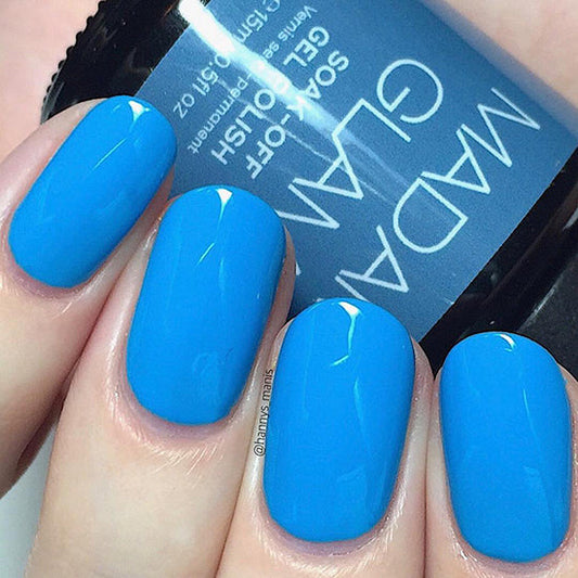Blue nail polish on nails with a visible brand name on the background