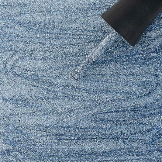 Close-up of a blue textured surface with a black object partially submerged.