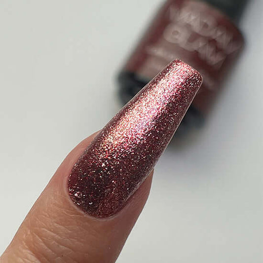 Nail with glittery pink polish on a neutral background