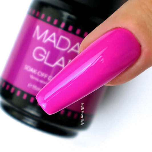 Pink nail polish on a hand with a Mada Glam product in the background