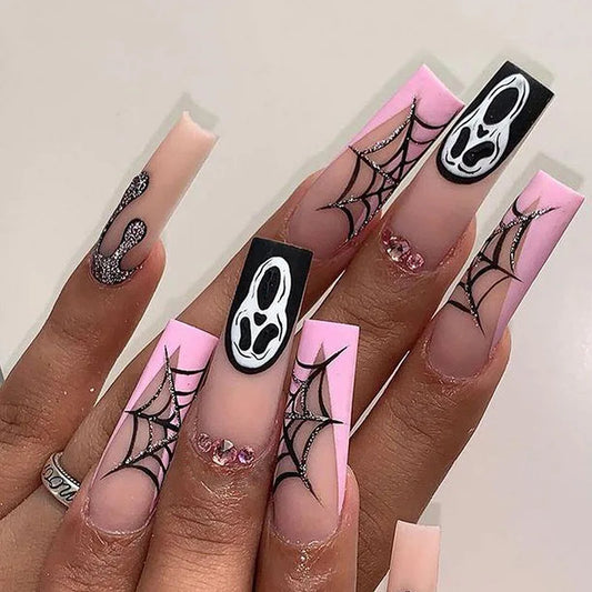 Halloween-themed nail art with spider webs and skull designs on pink and clear nails.