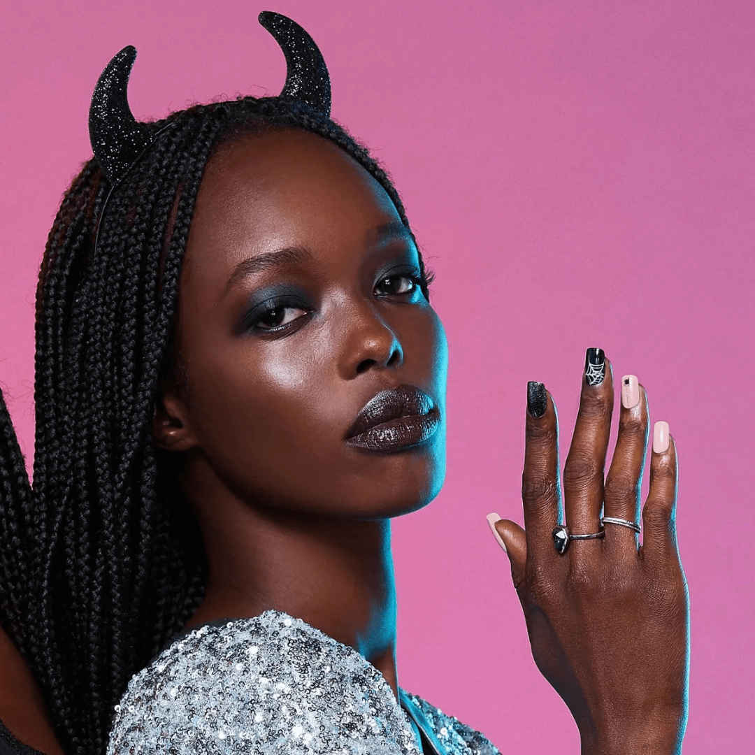 Woman with braided hair and black horns against a pink background