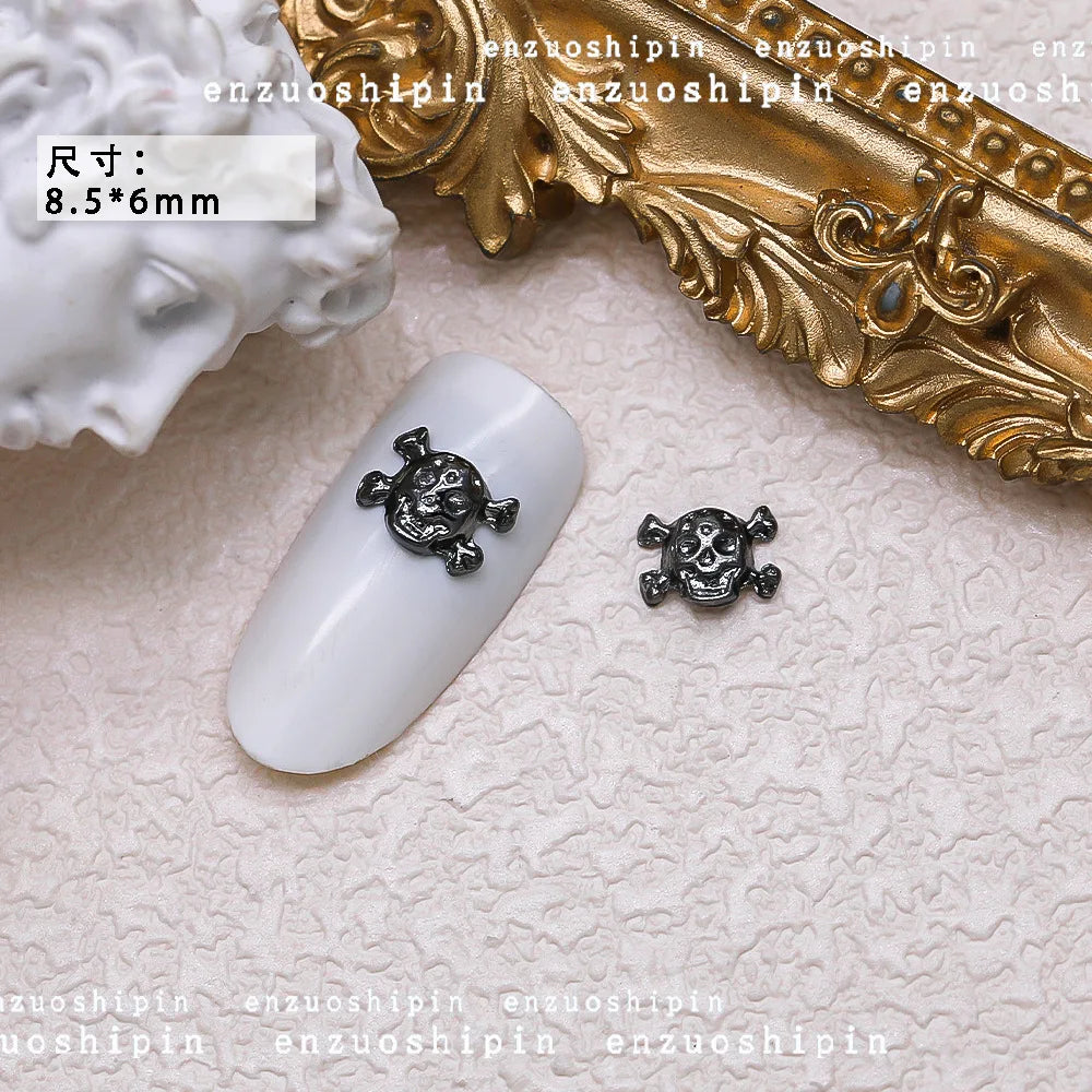 Nail art design with skull and crossbones on a white nail with gold decorative element.