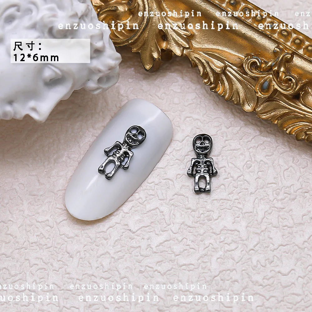 Small silver charms on a white nail with decorative gold object in the background