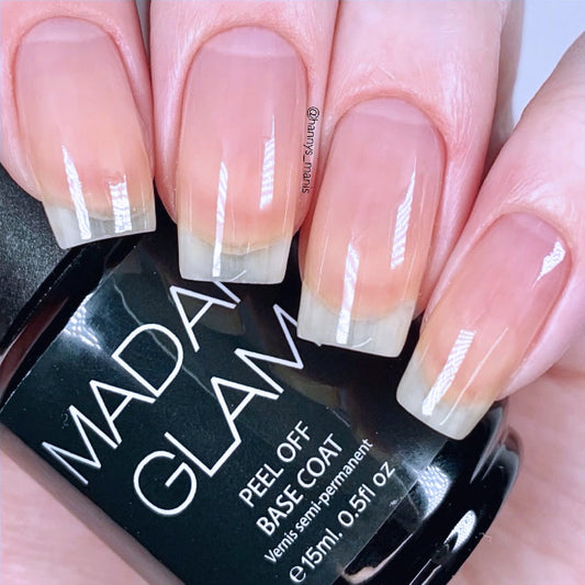 Nails with a gradient design held above a Madam Glam peel-off base coat bottle.