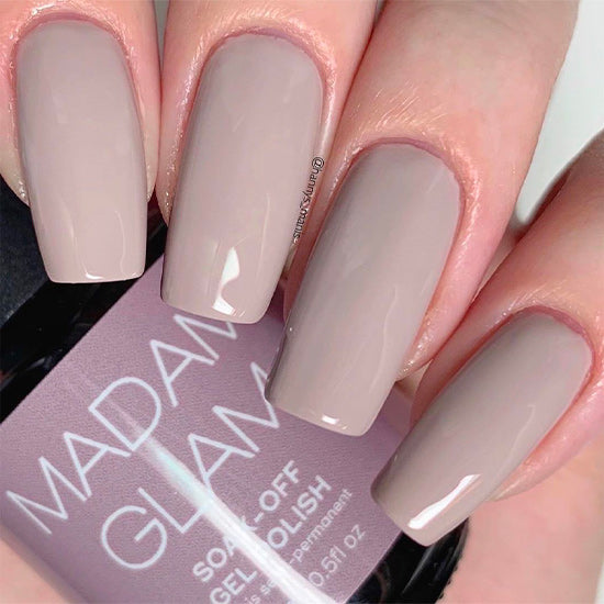 Nails with a neutral color scheme held over a bottle of Madam Glamour nail polish.