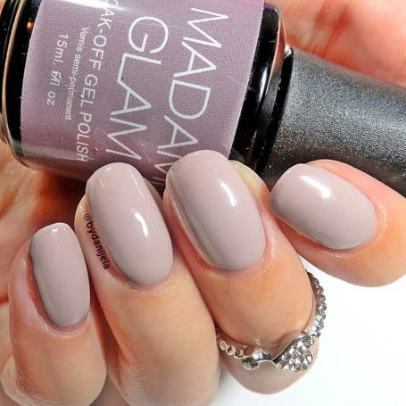 Hand holding a bottle of Madam Glam nail polish with matching nails.