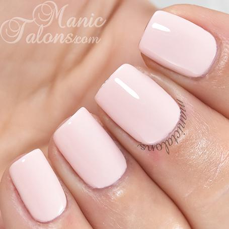 Close-up of a hand with pink nail polish on a blurred background, featuring the brand 'Manic Talons'.