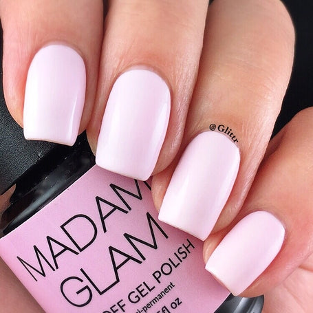 Nails with light pink polish held by a hand, with a Madam Glam nail polish bottle in the background.
